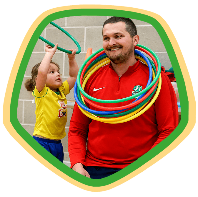 Little girl placing hoops over the neck of a SOCATOTS coach