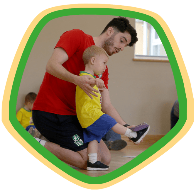 SOCATOTS coach guiding a toddler to kick a football